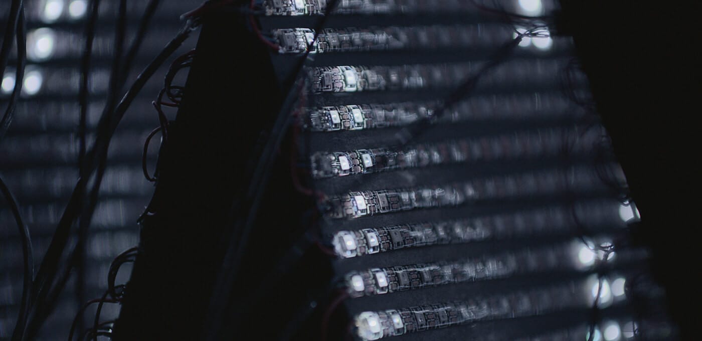 Close-up of stacked server blades in a dark data center, with glowing LEDs and cables running along the rack.