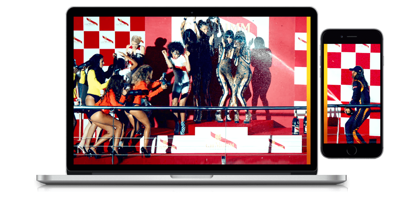 Laptop and smartphone screens show a fashion show with models dancing on a red carpet, a red-and-white checkered backdrop, and photographers.