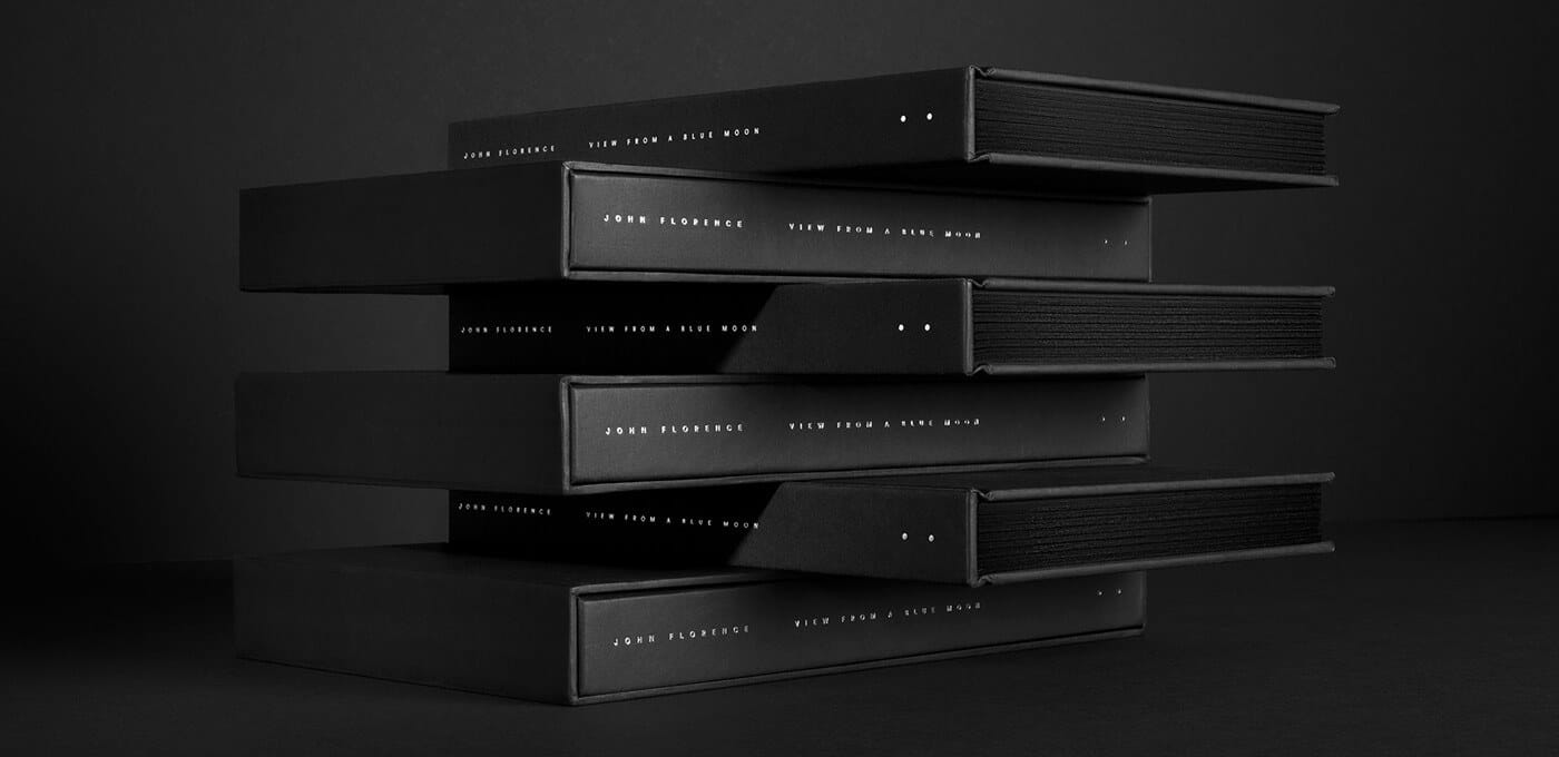 Stack of black hardcover boxes with white spine text, arranged in a staggered horizontal tower against a dark backdrop.